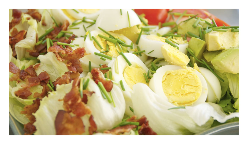An up-close image of a Cobb salad, with bacon, hard boiled eggs and avocado